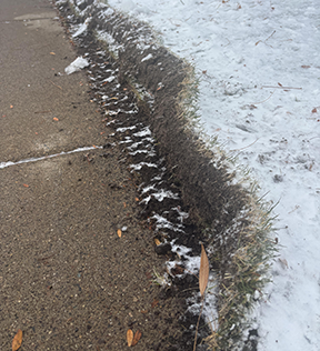 Snow covered sidewalk with difficult to see pavement edges